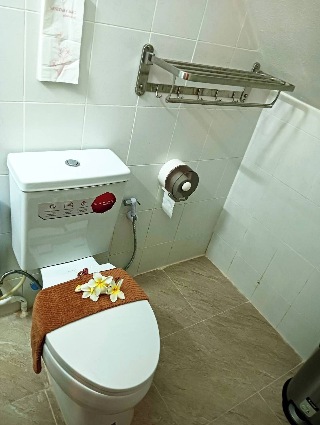 Ein Badezimmer mit Toilette, einem Händetrockner und einem Handtuchhalter.