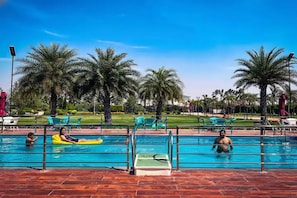 Piscina cercada por palmeiras e cadeiras de descanso.