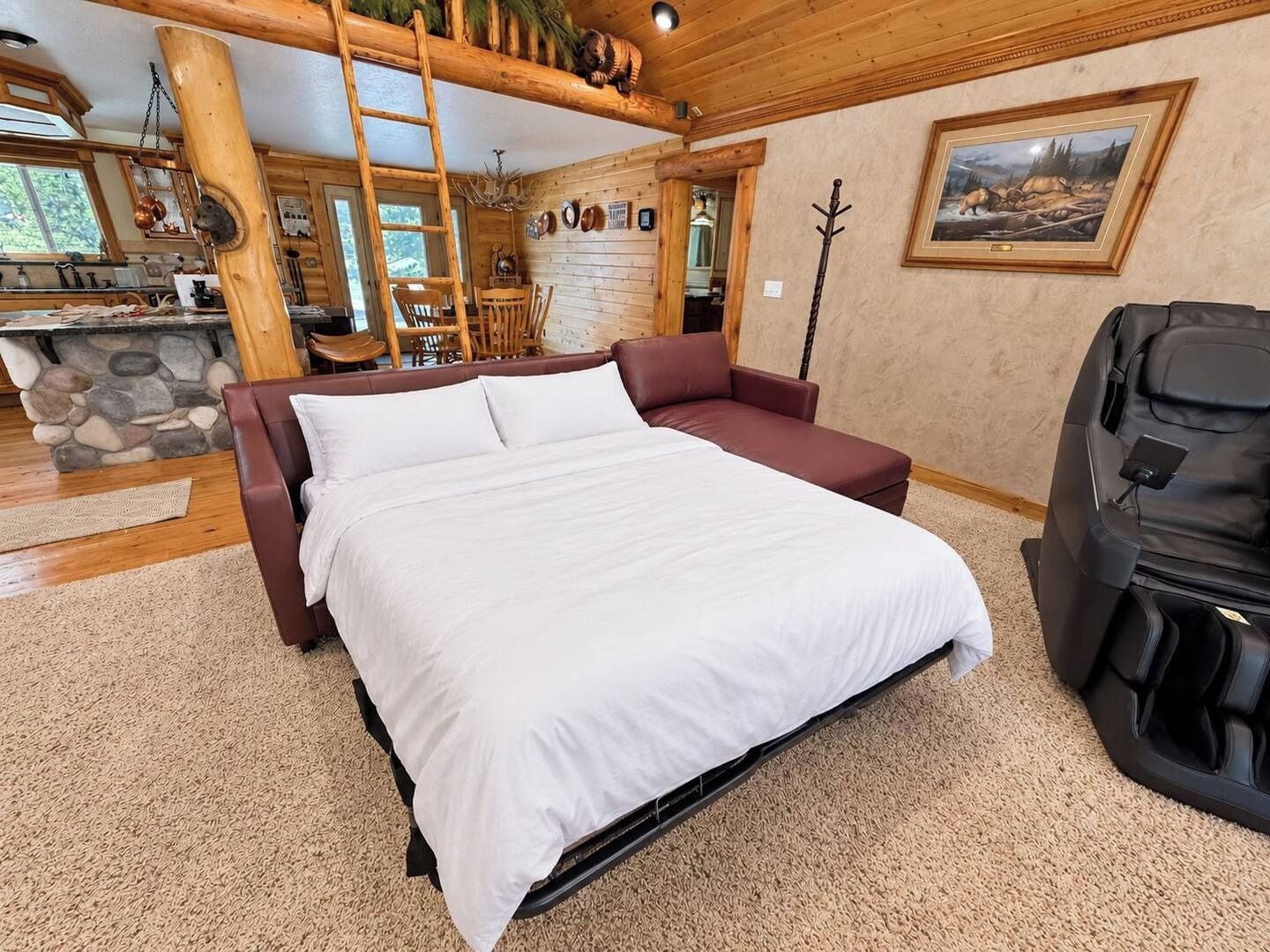 A bedroom with a bed, a sofa, a massage chair, a stone fireplace, and a painting on the wall.