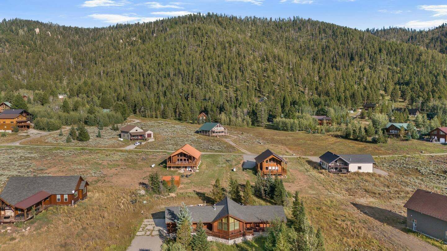 Um conjunto de chalés de madeira com uma paisagem montanhosa coberta por floresta.