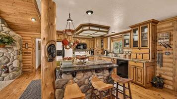 A rustic kitchen with wooden cabinets, a stone island, and bar stools.