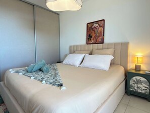 Een hotelkamer met een bed, nachtkastje, schilderij en een lamp.