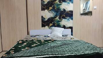 A bed with a floral bedspread and a patterned blanket, a wall with a marble-like design, and a mirror on the wall.