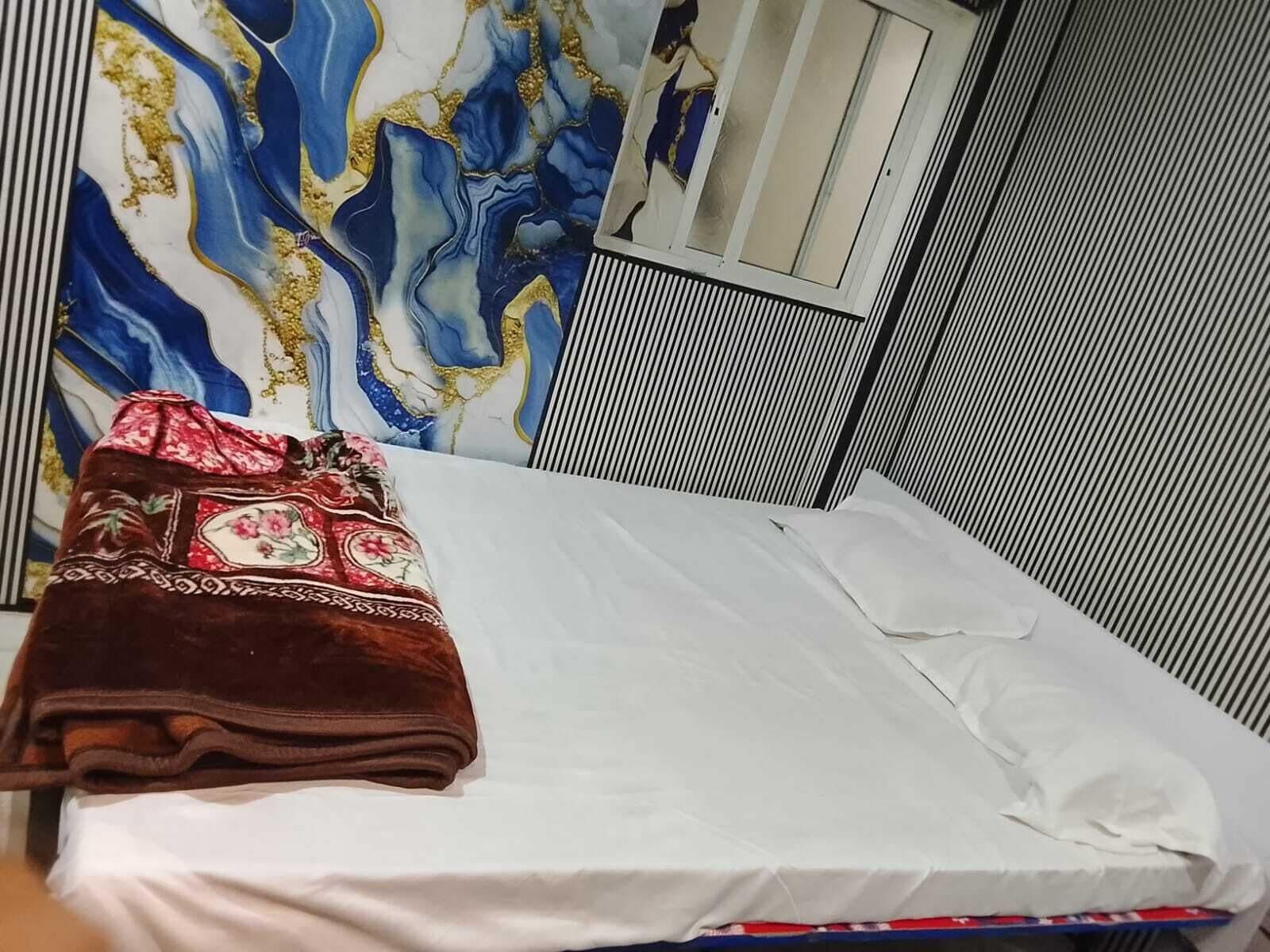 Una cama con sábana blanca y manta marrón estampada con motivos florales.