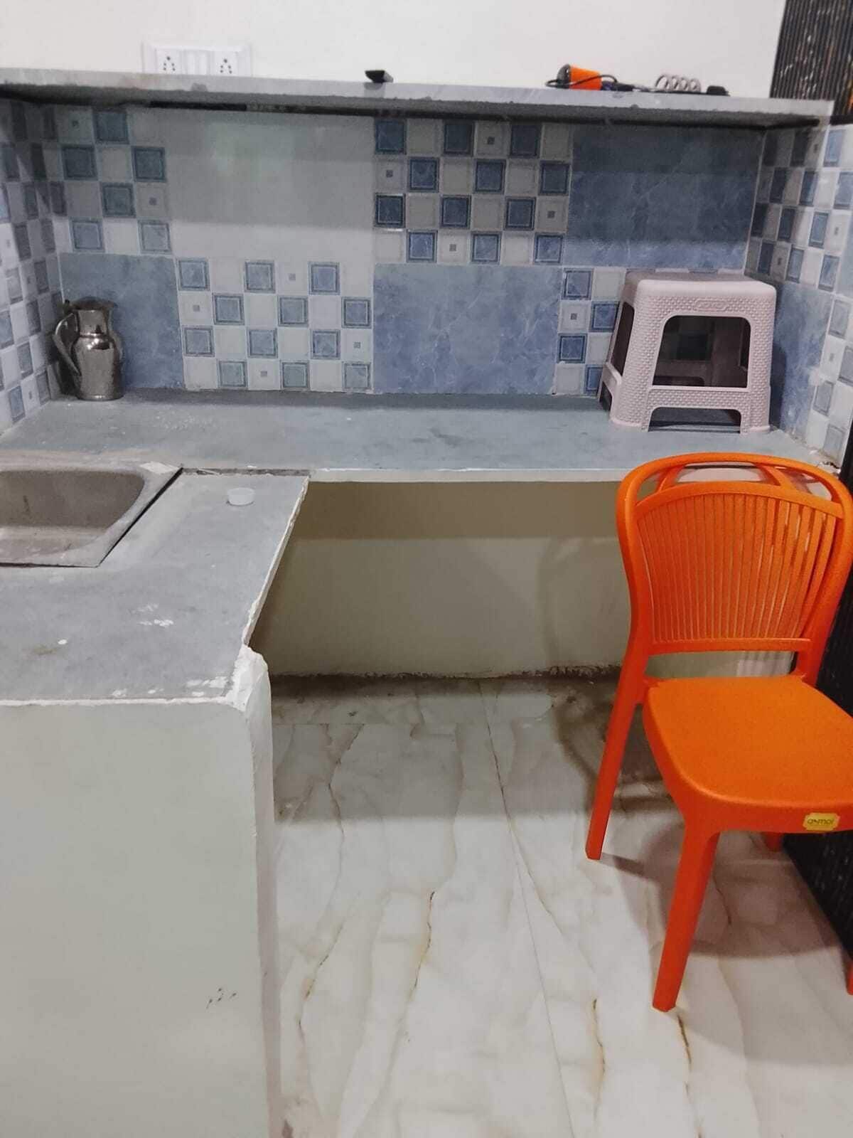 A kitchen with a sink, a small stool, and a chair.