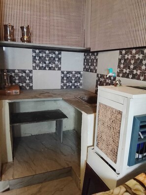 A compact kitchen with a built-in stove, a sink, and a small countertop. - Hotel Welcome (Indore)