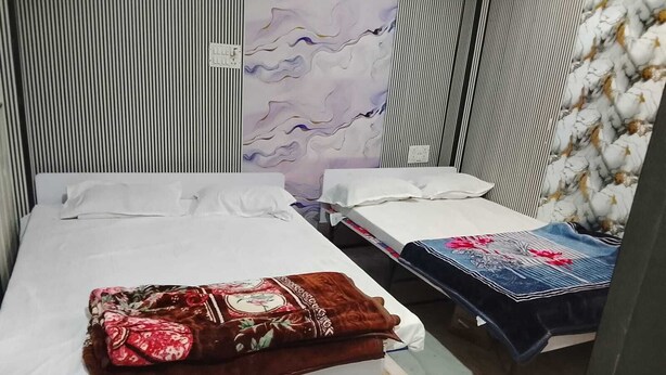 A room with two beds, one with a floral bedspread and the other with a denim cover. - Hotel Welcome (Indore)