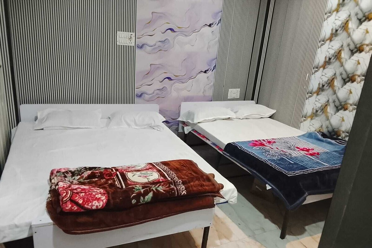 Una habitación con dos camas, una con cubrecama estampado y la otra con funda vaquera.