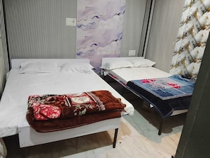 Quarto com duas camas, uma com colcha florida e outra com cobertura de jeans.