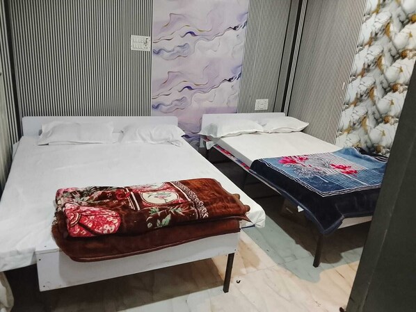 A room with two beds, one with a floral bedspread and the other with a denim cover. - Hotel Welcome (Indore)