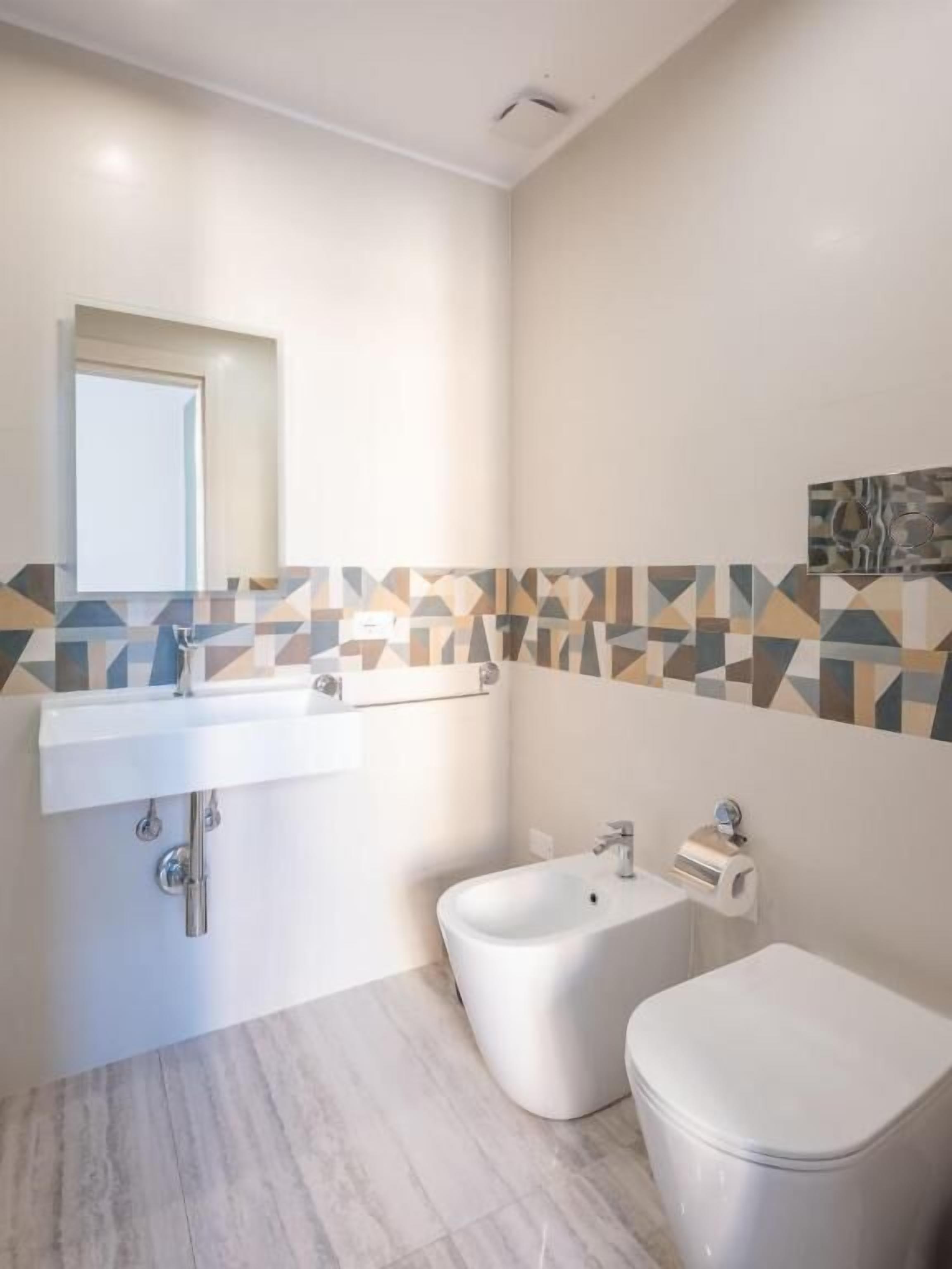 A bathroom with a white sink, bidet, and toilet.