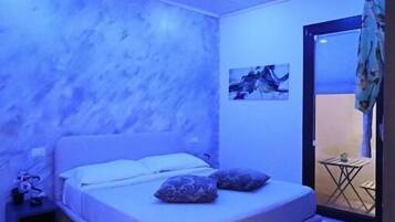 Un dormitorio con una cama, una mesita de noche y una pequeña mesa con una silla.
