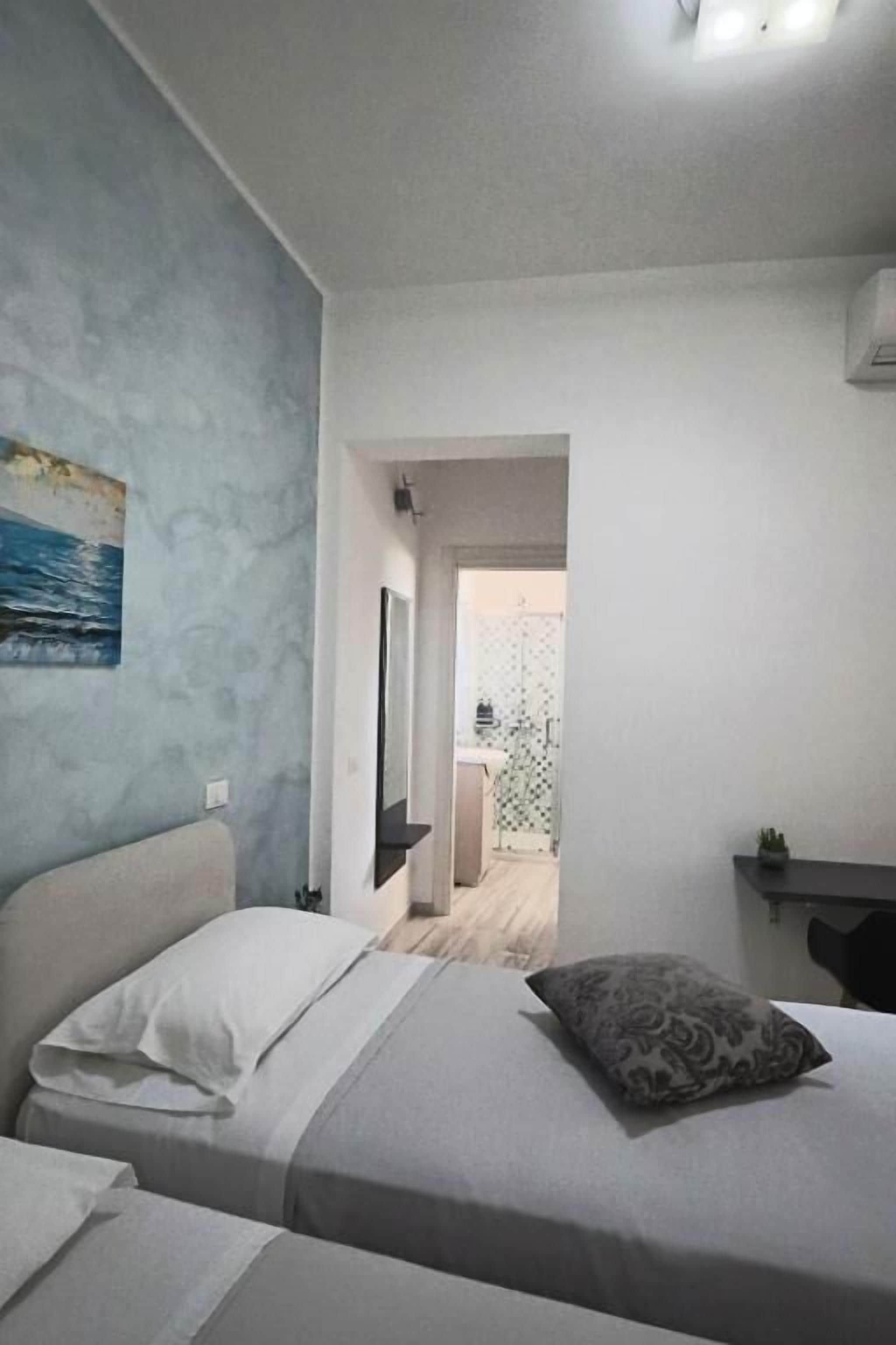 Een slaapkamer met een bed, nachtkastje en een schilderij aan de muur.
