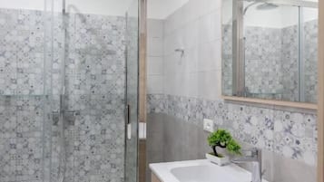 Un bagno moderno con doccia vetrata, lavandino bianco e mobile bagno in legno.