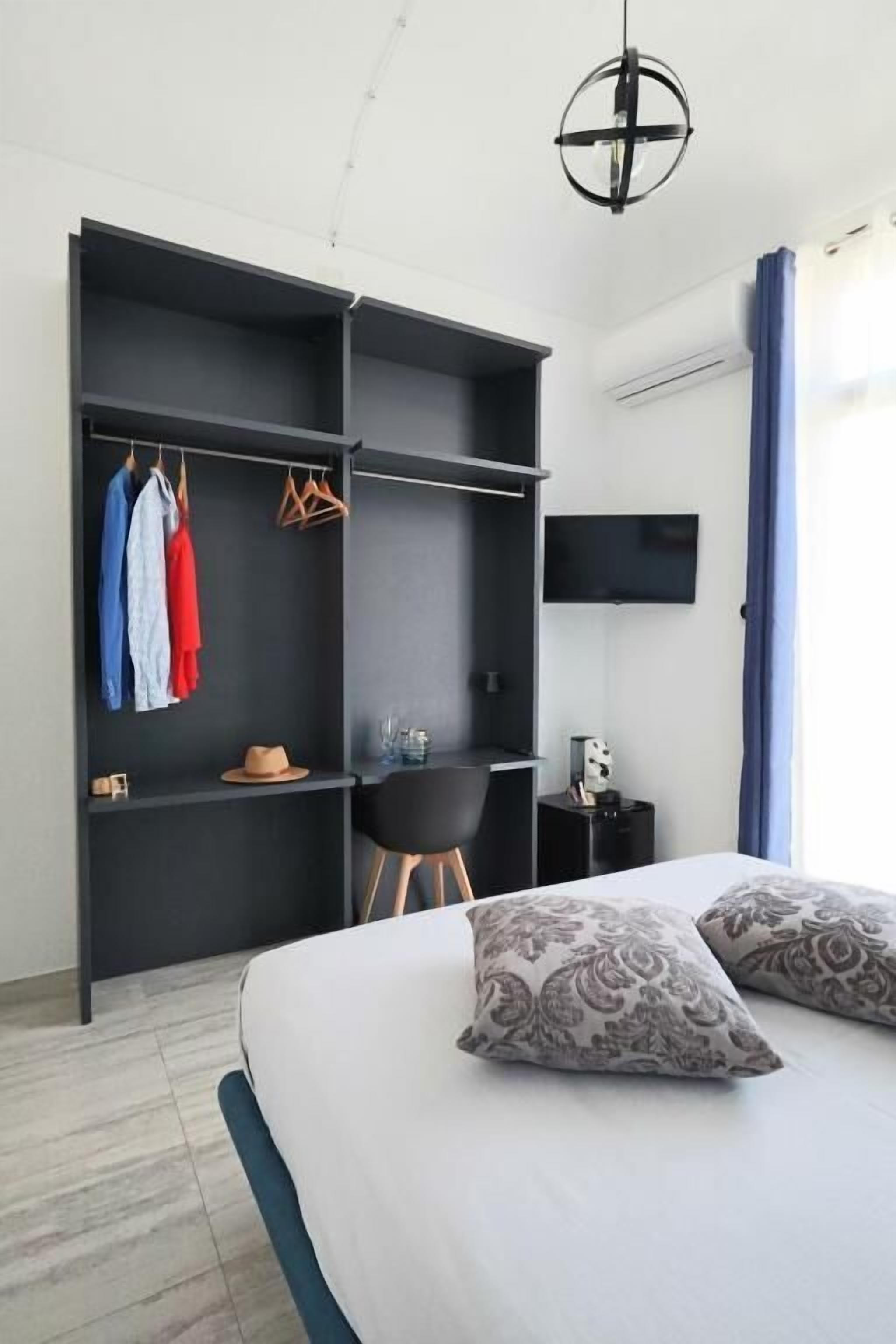 Habitación de hotel con cama, escritorio, silla y armario.
