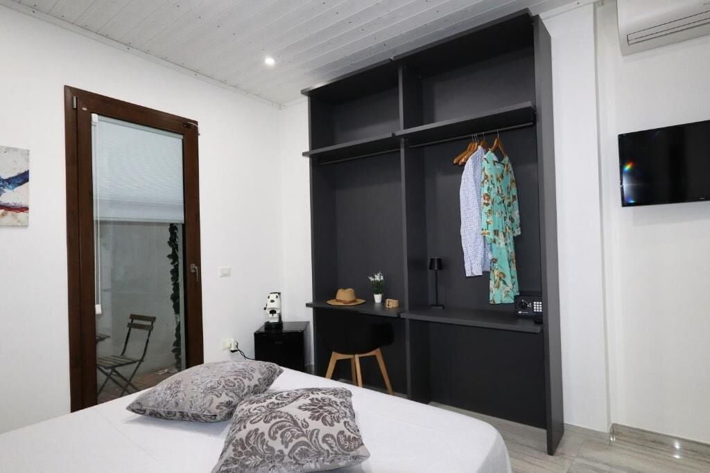 A bedroom with a bed, a wardrobe, a desk, and a TV.