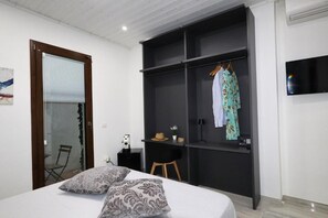 Un dormitorio con cama, armario, escritorio y televisor.