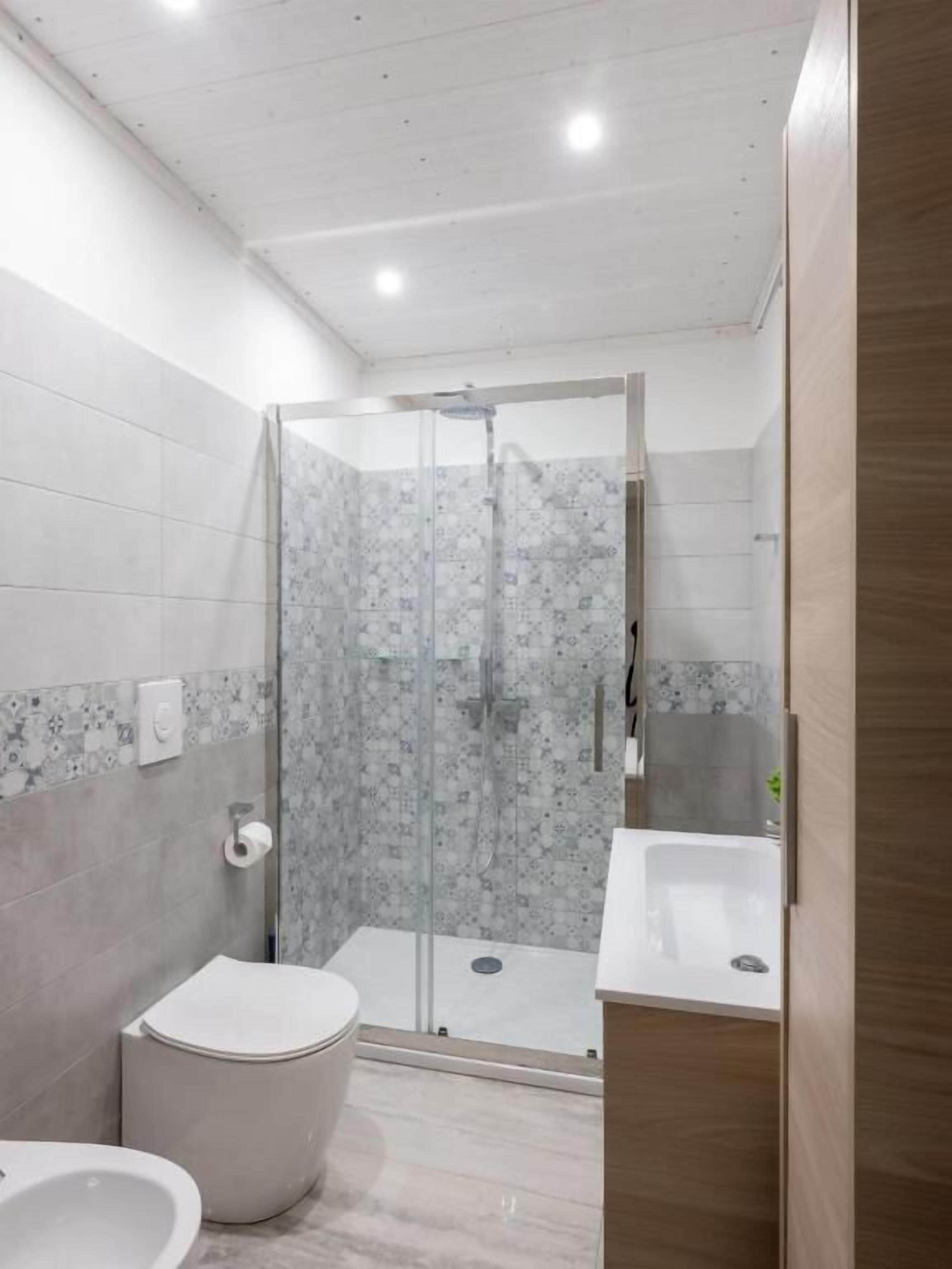 Ein modernes Badezimmer mit einer Duschkabine, einer Toilette und einem Waschbecken.