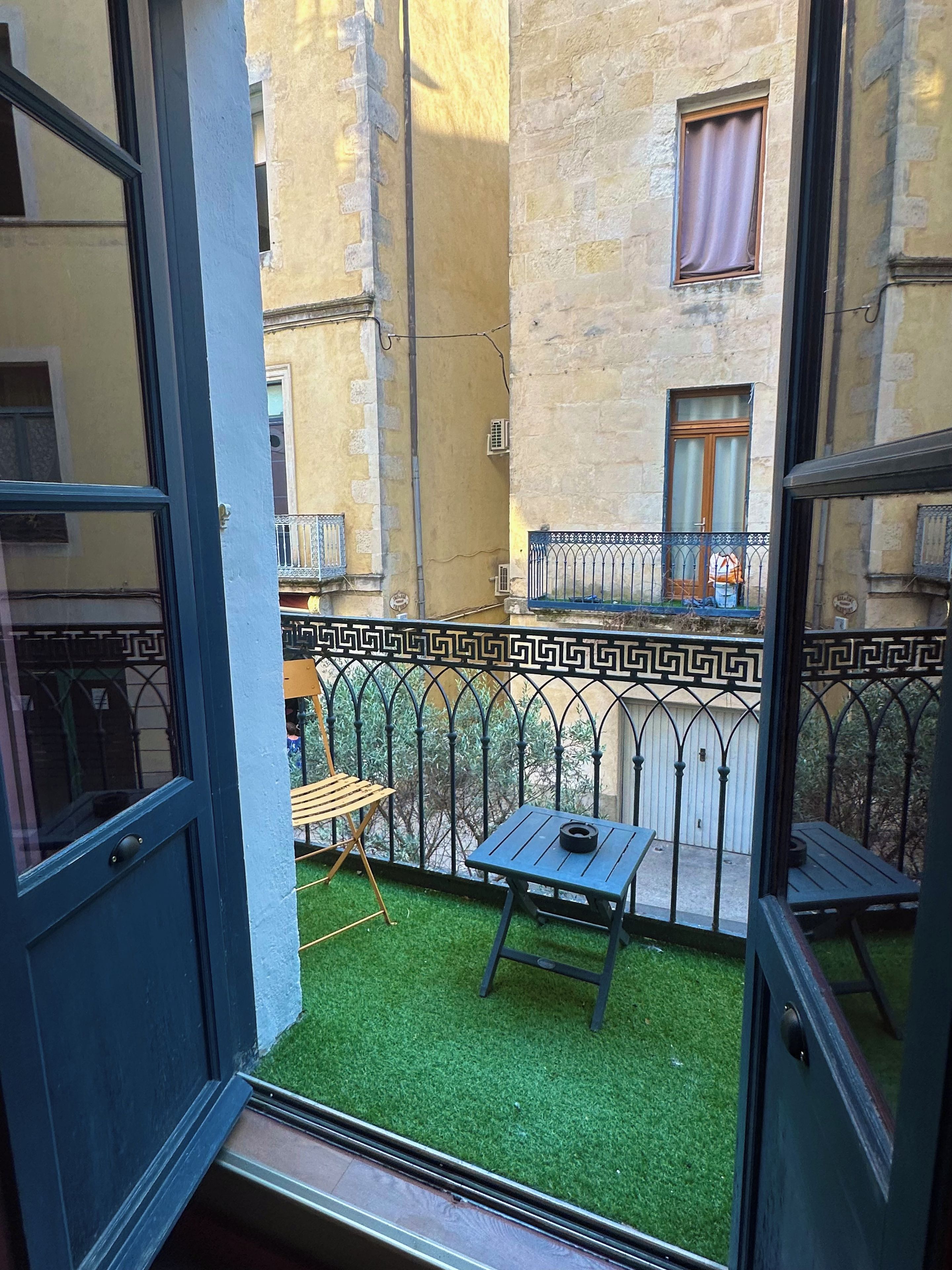 Een balkon met kunstgras, een kleine tafel en een stoel.