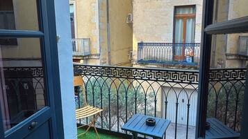 Een balkon met kunstgras, een kleine tafel en een stoel.