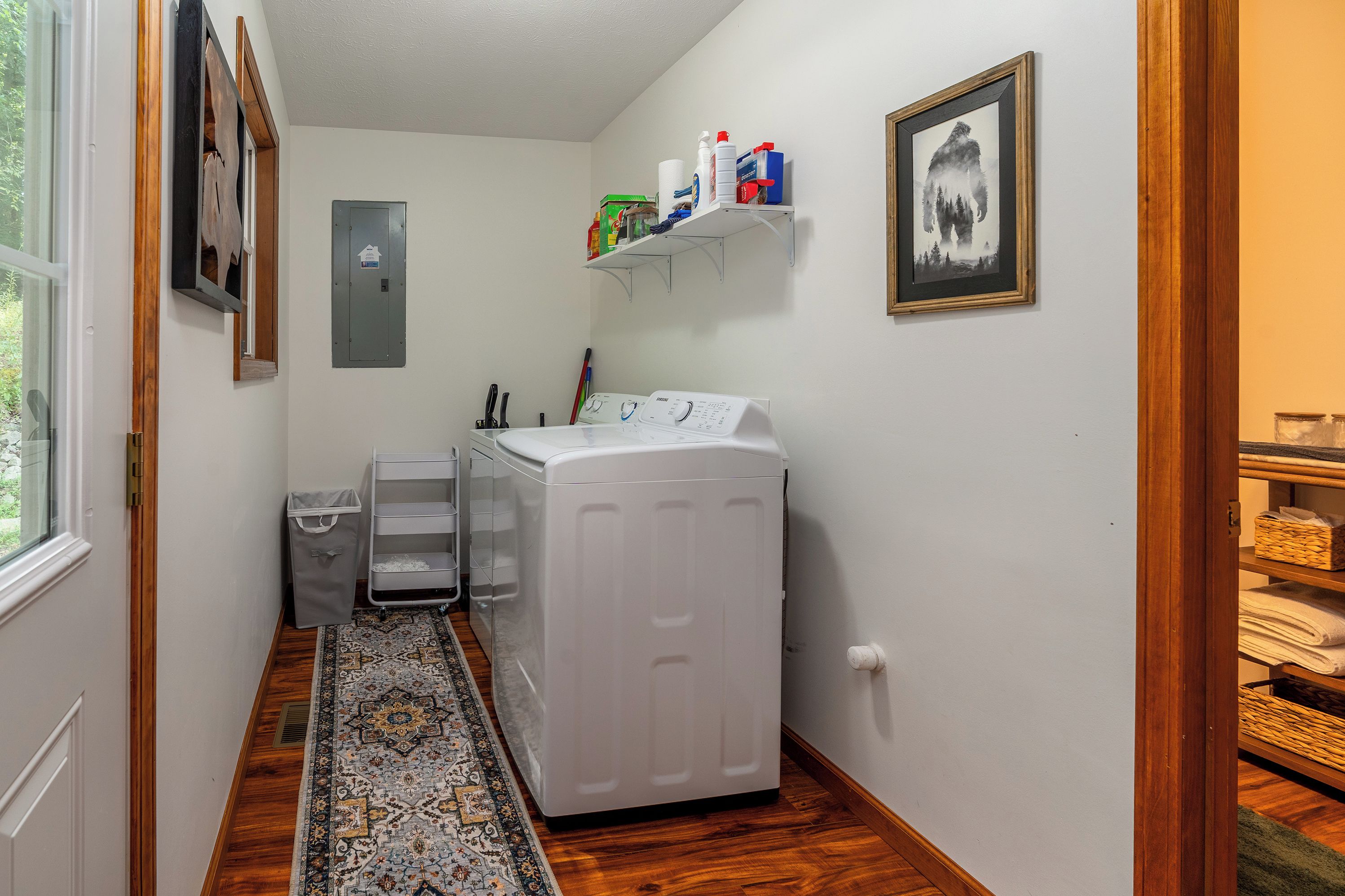 A laundry room with a washing machine, a drying rack, and shelves with cleaning supplies.