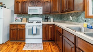 A kitchen with wooden cabinets, a white refrigerator, a microwave, a stove, and a sink.
