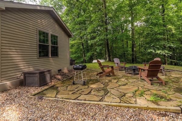A cabin with a stone patio, outdoor seating, and a grill.