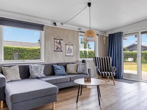 Un salon moderne avec un canapé d’angle gris, une table basse ronde et un fauteuil à rayures.