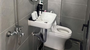 Een badkamer met douche, toilet, wastafel en spiegel.