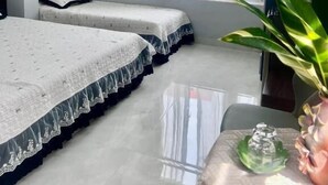 Een hotelkamer met twee bedden, een raam met gordijnen, een plant en een kleine tafel met een vaas.