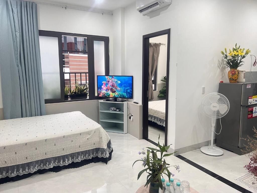A hotel room with a bed, a television, a fan, and a view of the outside.