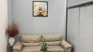 A modern living room with a beige sofa, a round coffee table with a vase of flowers, and a framed artwork on the wall.