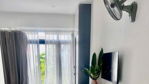 Een hotelkamer met een bed, een bureau met stoel, een televisie en een raam met gordijnen.
