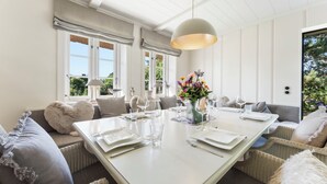 Un espace repas avec une grande table dressée pour six personnes, entourée de canapés et de fauteuils.