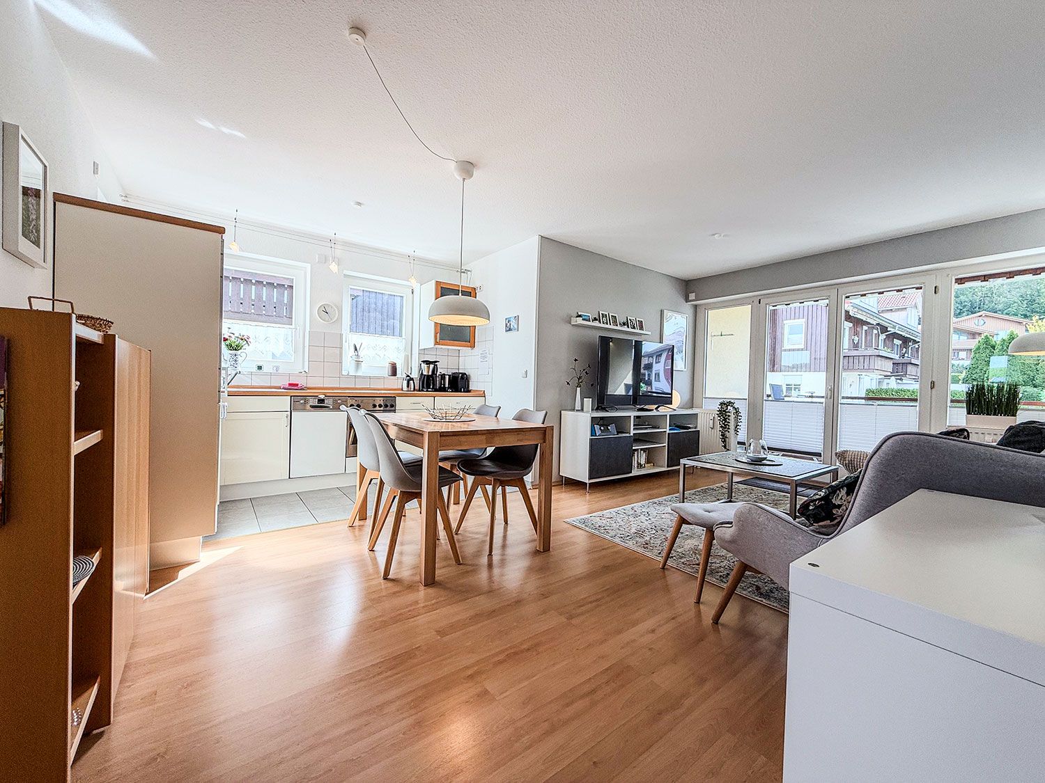 A modern living space with a dining area, kitchen, and a large window offering a view of the outside.