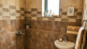 Een badkamer met een douche, wastafel en een raam.