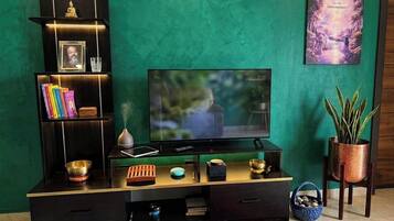Ein Wohnzimmer mit Fernseher, Bücherregal und Dekorationselementen.