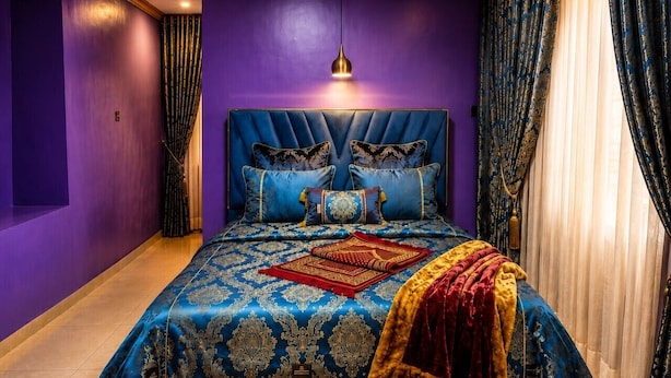 Een slaapkamer met een groot bed, paarse wanden en een kroonluchter.