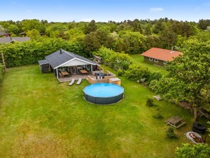 Una propiedad residencial con piscina, patio cubierto y jardín cercado.
