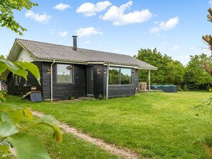Una casa de un piso con fachada oscura, ventanas amplias y una chimenea visible.