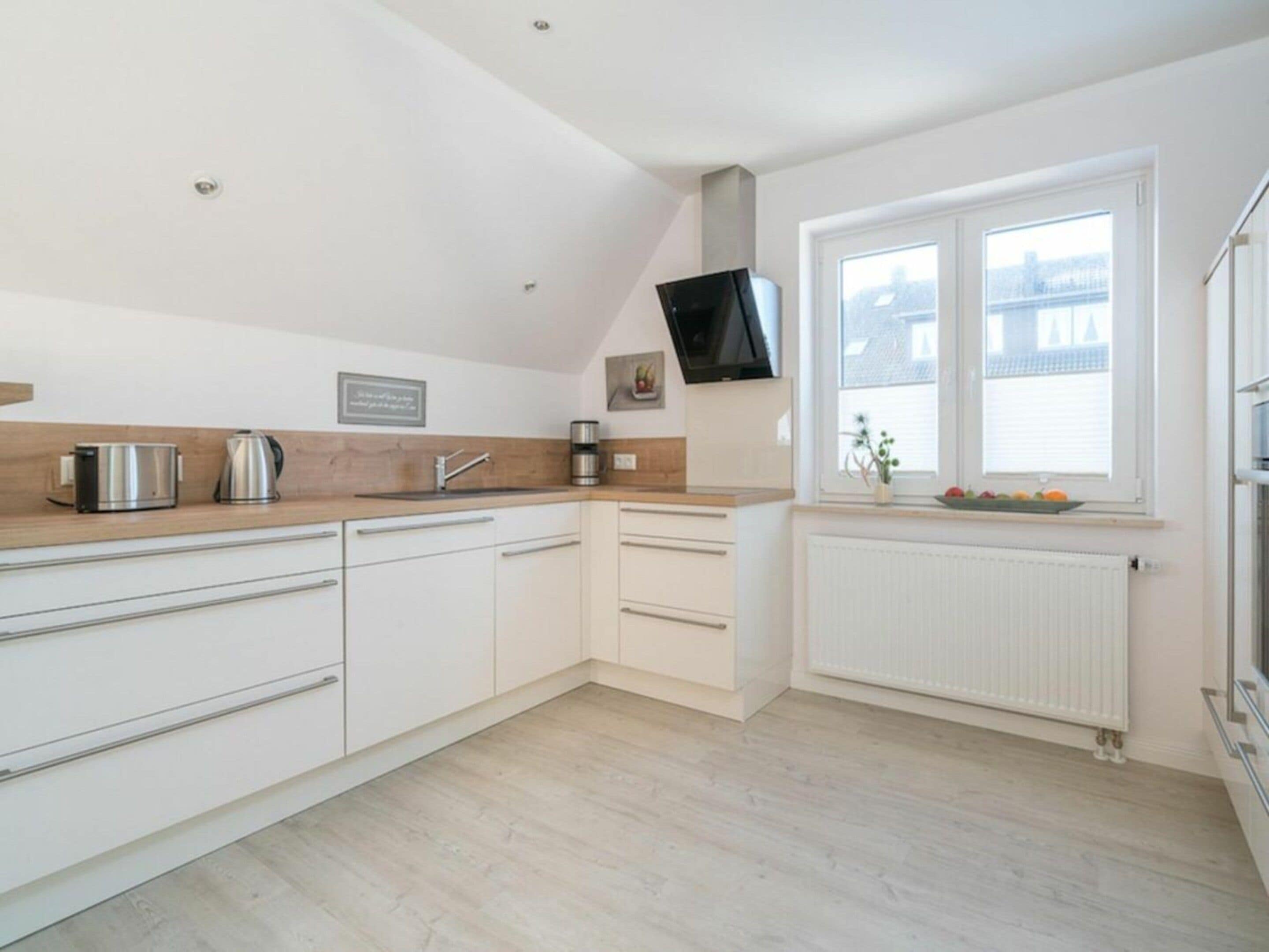Una cocina moderna con armarios blancos, encimera de madera, estufa integrada y ventana con vistas.