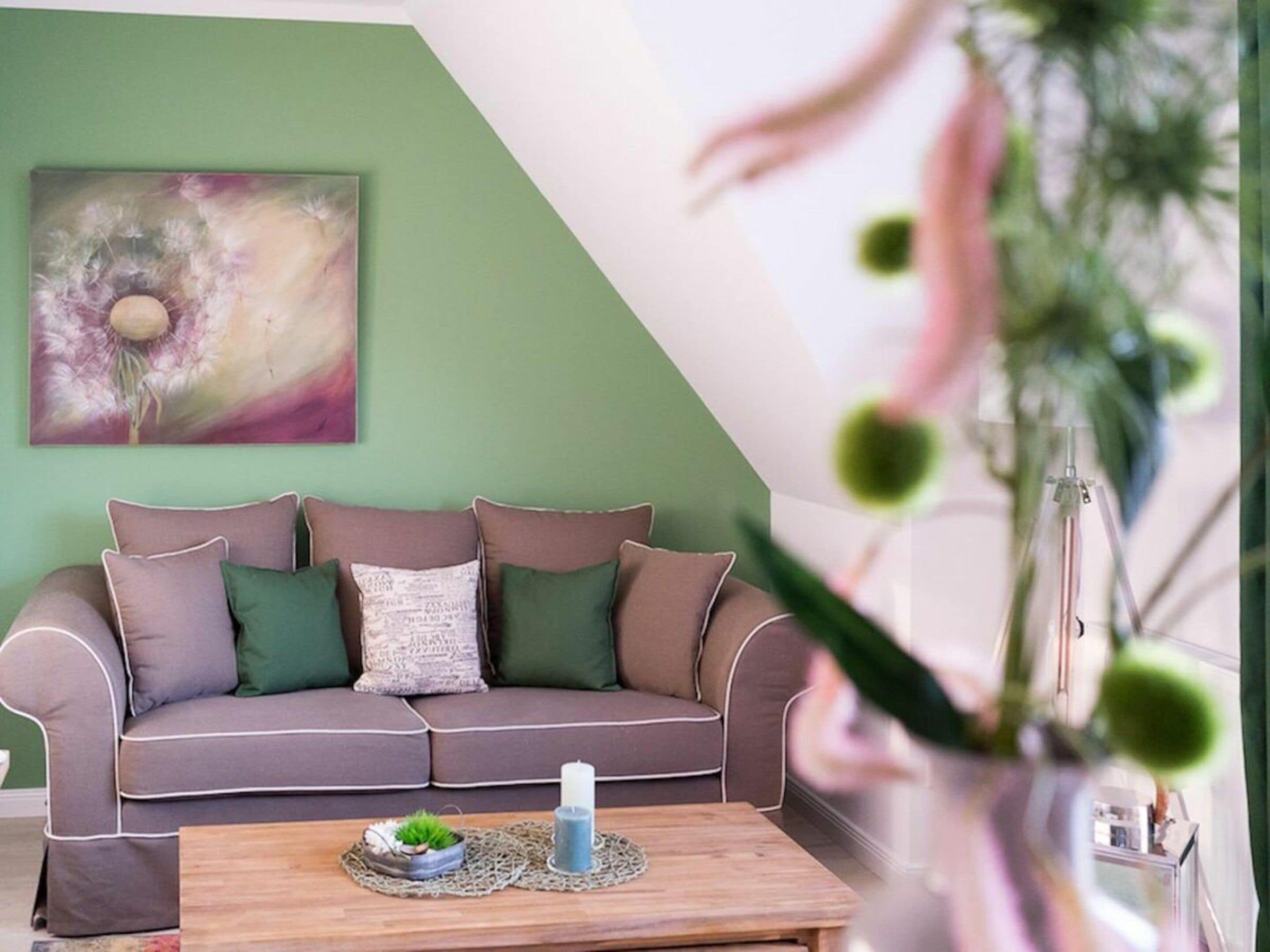 A living room with a sofa, a coffee table, and a wall painting.