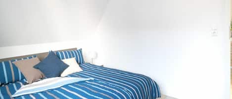 A bedroom with a bed, pillows, and a bedside table.