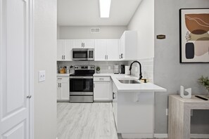 A modern kitchen with white cabinetry, stainless steel appliances, and a white countertop. - Location • Pool • Lux Gym • Free Parking • Cozy Retreat • Fireplace (Phoenix)