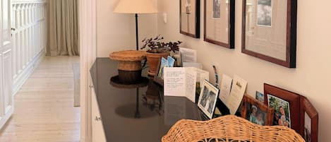 A hallway with a black countertop, wicker baskets, framed pictures, and a lamp.