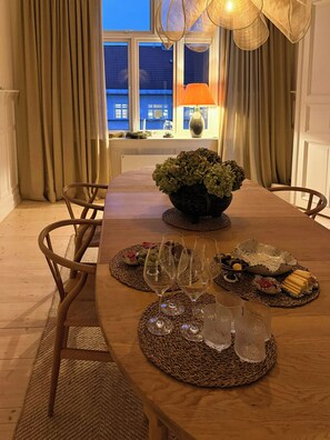 A dining table set with a bowl of green foliage, wine glasses, and a variety of food items.