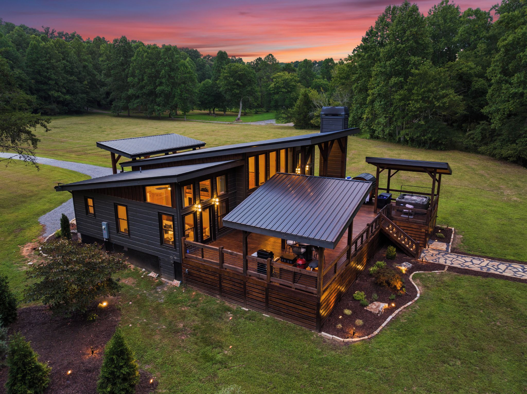 A modern two-story house with a deck, large windows, and a well-maintained lawn.