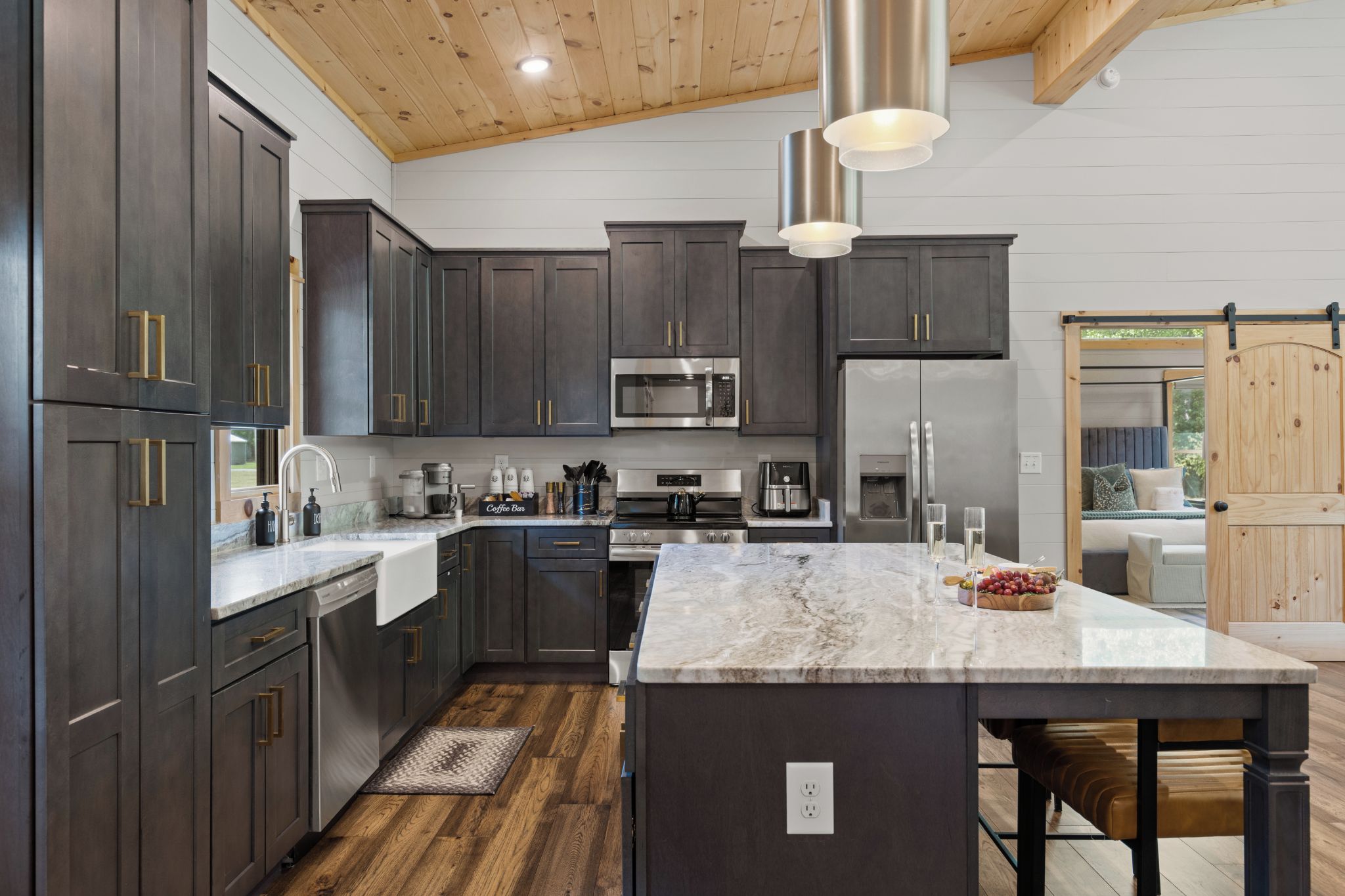 A modern kitchen with dark cabinetry, stainless steel appliances, and a marble island.