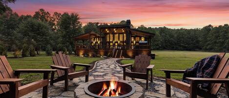 A wooden cabin with a fire pit and outdoor seating.