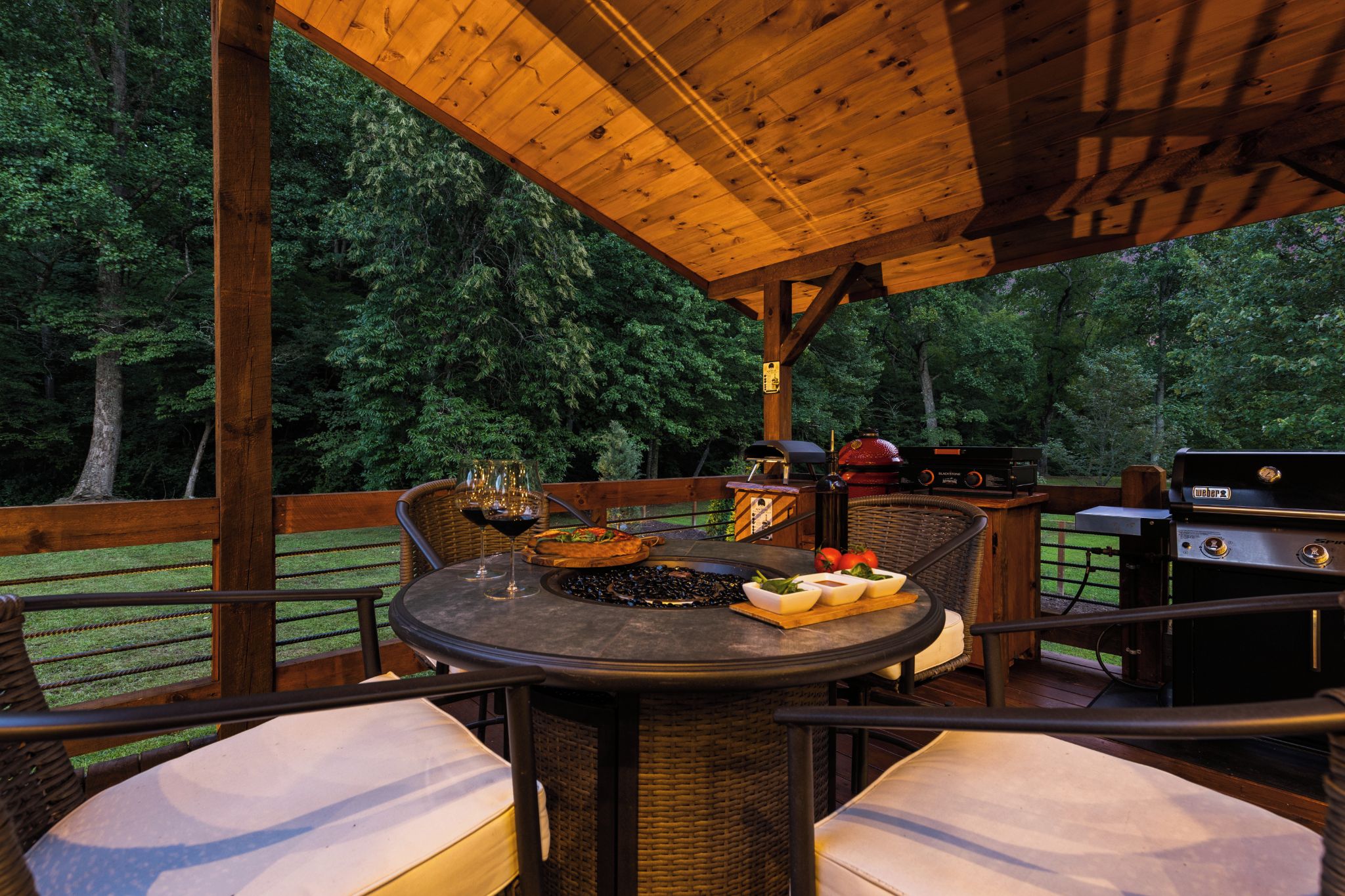 An outdoor patio with a round table, wicker chairs, and a grill.